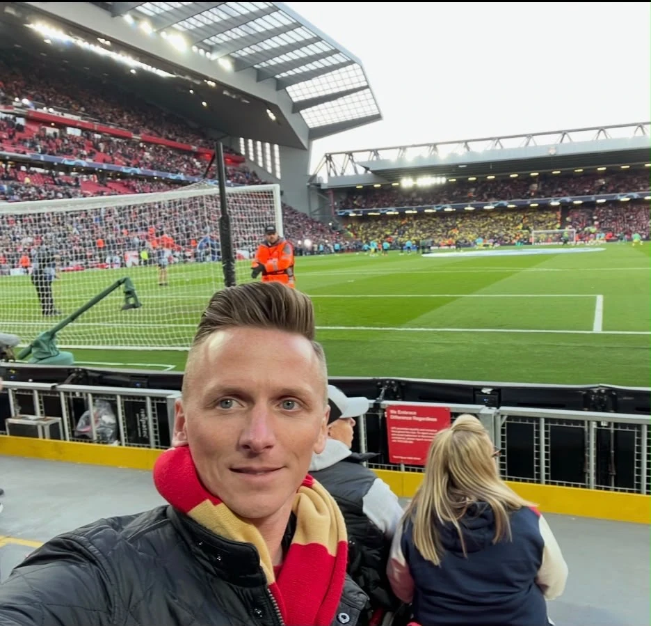 A matchday selfie from the stands, with the pitch and supporters behind